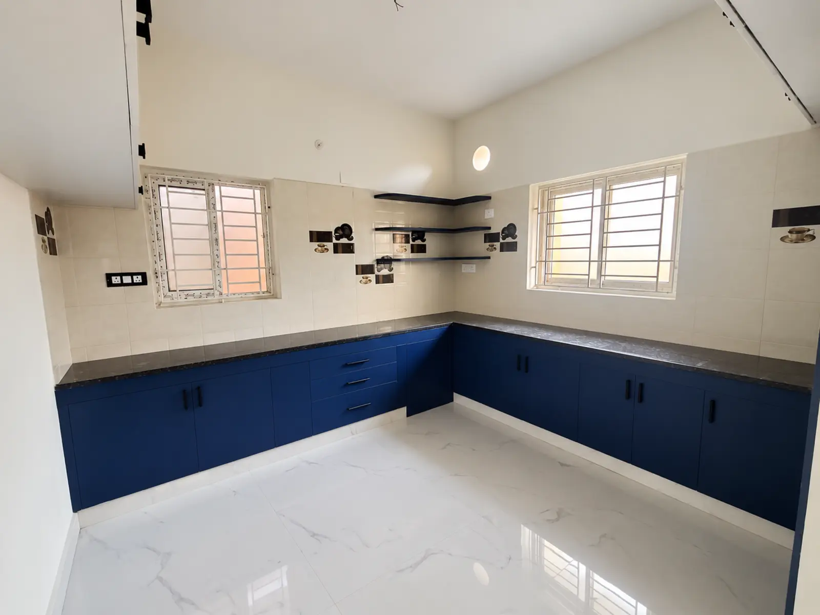 Blue L-shaped semi-modular kitchen with open shelves in the completed VIVA VINNA apartment, Pozhichalur, Chennai